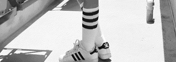 A photo of legs donning Adidas sneakers and socks on a building rooftop.