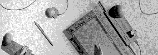 An assortment of corded trackballs and plastic styluses around a flat classic MacPaint screen